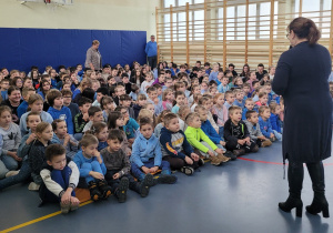 Pani dyrektor przemawia do zgromadzonej na sali gimnastycznej społeczności uczniowskiej podczas apelu.