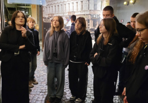 Uczniowie uważnie słuchaja pani przewodnik w Muzeum Powstania Warszawskiego.