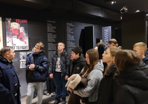 Uczniowie na Pawiaku zasłuchani w opiwieści przewodnika.