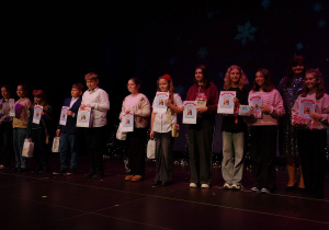 Wszyscy nagrodzeni nasi uczniowie w konkursie plastycznym na scenie z nagrodami.