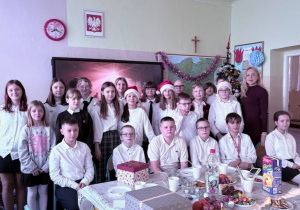 Wigilia w klasie 5a. Uczniowie z wychowawcą na tle choinki.