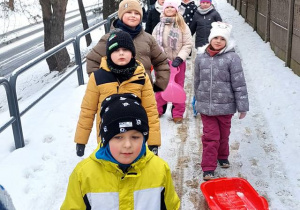Uczniowie z sankami w drodzę na śnieżne zabawy.