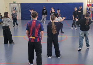 Uczniowie na sali gimnastycznej podczas aktywności fizycznej - gra w Dwa Ognie.