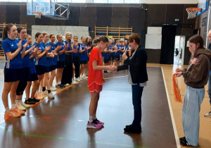 Emilia Liwczyńska odbiera dyplom za zajęcie drugiego miejsca w zawodach koszykówki.