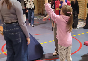 Zajęcia sportowe na sali gimnastycznej. dzieczynka rzuca do kosza.