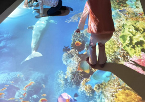 Dzieci na magicznej podłodze łapią ryby na rafie koralowej.