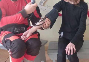 Ratownik medyczny mierzy ciśnienie uczennicy.