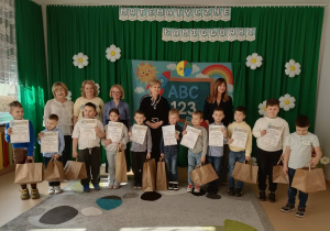 Duża grupa wyróżnionych uczniów w konkursie matematycznym. Każdy uczeń ma w dłoni dyplom i torbę z nagrodami.