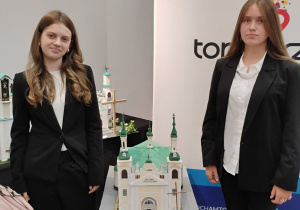 Oliwia i Zuzia stoją przy swojej nagrodzonej pracy plasycznej - makieta kościołą