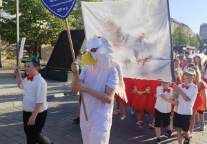 Uczeń z twarza orła niesie tarczę SP 14 podczas parady z okazji Dni Tomaszowa