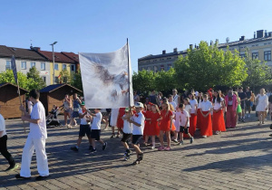 Uczniowie trzymają w górze baner z patronem szkoły - Orzeł Biały