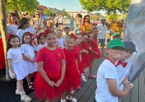 Uczennice w czerwonych i białych strojach w oczekiwaniu na przemarsz podczas parady