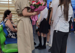 Uczniowie klas ósmych wręczaja kwiaty dyrekcji.