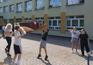Uczniowie grają w baloniadę - przerzucają balon napełniony wodą za pomocą ręcznika