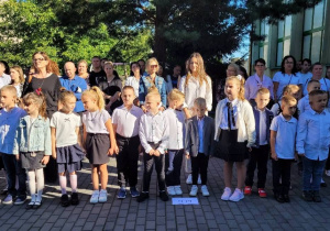 Duża grupa dzieci- klasa pierwsza podczas rozpoczęcia roku szkolnego.