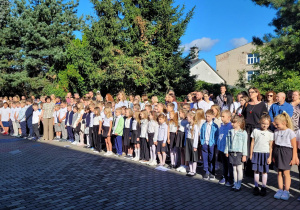 Duża grupa uczniów na wybiegu szkolnym podc zas uroczystego rozpoczęcia roku szkolnego.
