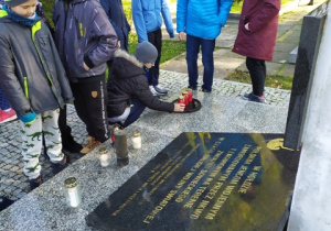 Uczniowie klasy VB zapalają znicze na pomniku poświęconym Jeńcom Wojennym