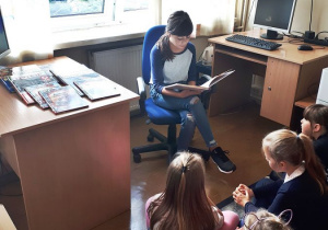 Uczennica czyta dzieciom z klasy pierwszej.