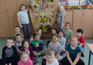 Wnętrze klasy. Grupa uczniów pozuje do zdjęcia. Trzy dziewczynki i dwóch chłopców stojący po bokach trzyma wielki plakat.