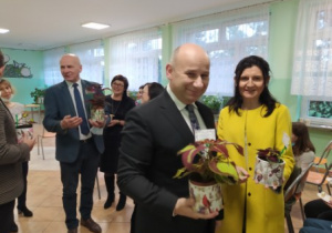 Prezydent Miasta Pan Marcin Witko i Pani Beata Stańczyk trzymają w dłoniach roślinki w doniczkach.. W tle mężczyzna i kobieta.