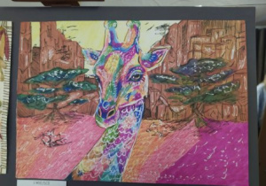Bardzo kolorowa praca plastyczna namalowana mazakami. Na pracy jest żyrafa.