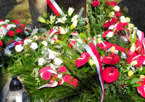 Bukiety biało - czerwonych kwiatów złożone przed pomnikiem poświęconym pamięci Polaków ratujących Żydów