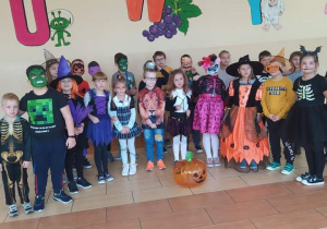 Grupa uczniów z klasy 2 w strojach halloweenowych stoi na tle ściany.