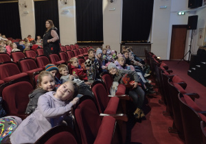 Wnętrze teatru .Na widowni , na czerwonych fotelach siedzą uczniowie.