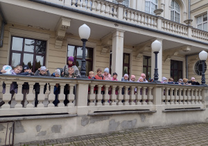 Uczniowie stoją na tarasie przed teatrem. W tle ściana teatru.