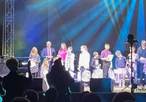 Duża grupa dzieci stoi na scenie.