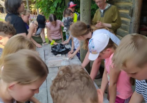 Przed chatą garncarza. Uczniowie zgromadzeni wokół stołulepia w glinie.