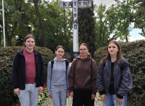 Czterech uczniów stoi przy Pomniku Ofiar Katynia