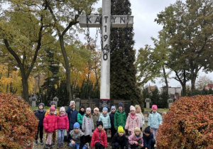 Dzieci na cmentarzu zapalają znicze na grobach żołnierzy