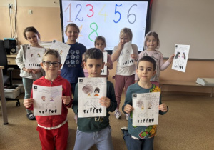 Dzieci pozują z wykonanym zadaniem w kartach pracy