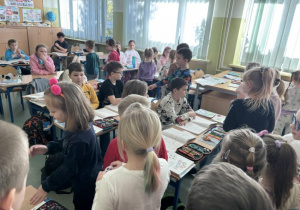 Dzieci wręczaja Usmiechnięte buźki uczniom klasy III