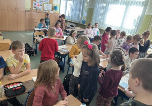 Dzieci wręczaja Usmiechnięte buźki uczniom klasy III