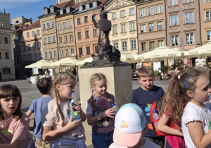 Grupa uczniów przy pomniku Syrenki w Warszawie.