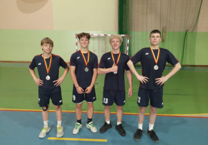 Dumni uczniowie w strojach sportowych z medalami na klatce piersiowej. Od lewej: Eryk, Bartek, Olaf i Dawid.