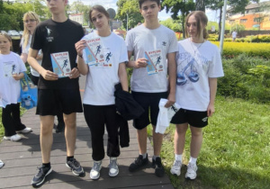 Dwie dziewczyny i dwóch chłopców w okazjonalnych koszulkach i z dyplomami za udział w biegu.