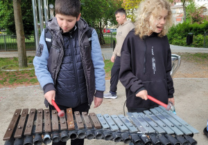 Uczen i uczennica grają na cymbałkach w muzycznym placu zabaw.