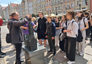 Uczestnicy wycieczki zasłuchani w opowieści przewodnika na temat Gdańska.