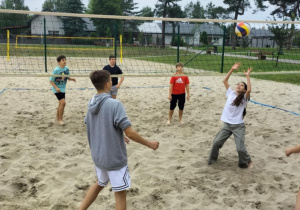Grupa uczniów klasy 6b podczas gry w siatkówke plażową.