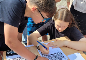 Czterech uczniów klasy 7b podczas rozwiązywania zagadki z kodem QR.