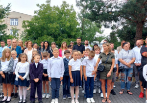 Duża grupa uczniów klasy drugiej wraz ze swoimi rodzicami podczas rozpoczęcia roku.
