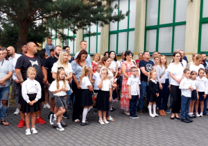 Duża drupa uczniów klasy pierwszej wraz ze swoimi rodzicami na apelu inauguracyjnym 1 września.
