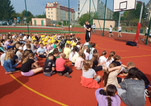 Duża grupauczniów na boisku szkolnym podczas spotkania z koszykówką.