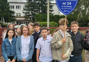 Grupa uczniów z emblematem szkoły podczas urodzystości pariotycznej.