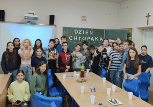 Duża grupa uczniów i uczennic klasy 6a, na tablicy napis Dzień Chłopka. Chłopcy z medalami na szyjach.