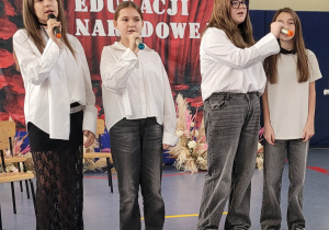 Cztery dziewczynki śpiewają piosenkę dla nauczycieli.