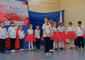 Uczniowie klasy 2a odświętnie ubrani na tle dekoracji z okzji Święta Niepodległości.